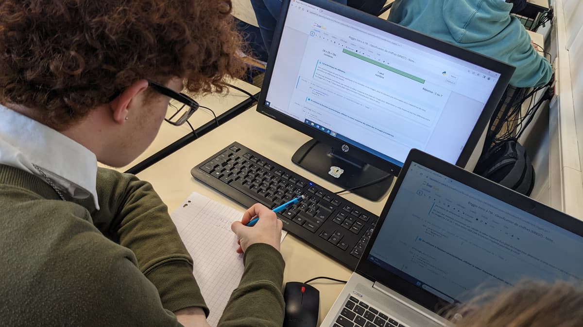 Elève alliant exercice numérique et travail sur papier